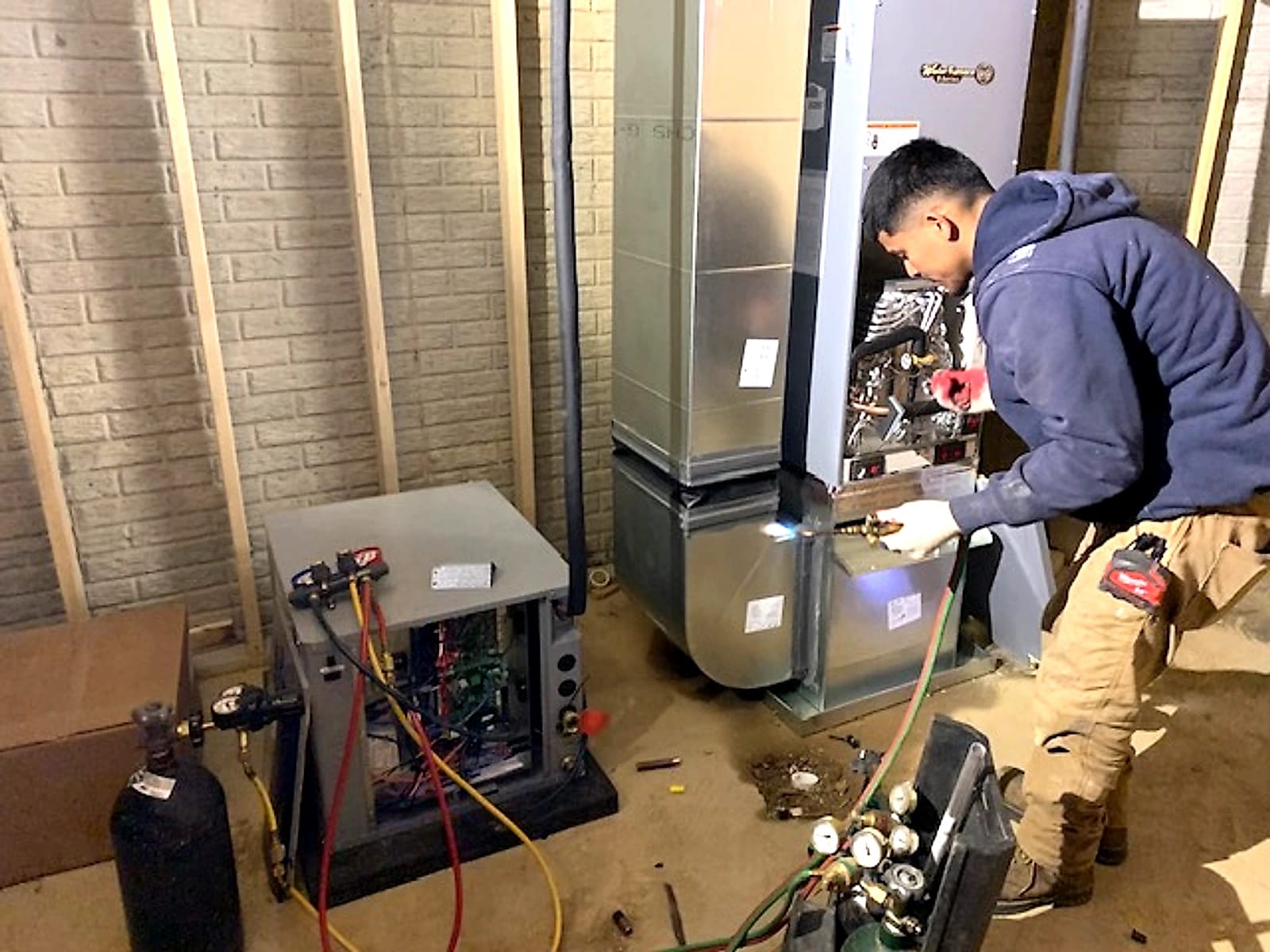 A North American GeoThermal technician brazing a line on a geothermal unit in a basement